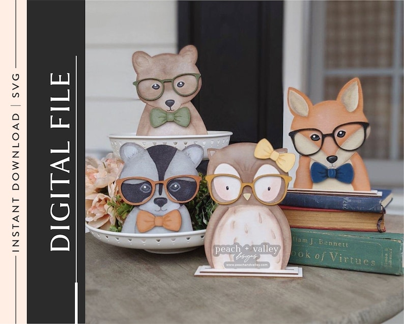 May include: A set of four wooden animal figurines wearing glasses and bow ties. The animals are a raccoon, an owl, a fox, and a bear. The figurines are arranged on a tiered cake stand with a floral arrangement in the background. The text "peach + valley designs" is visible on the base of the owl figurine.