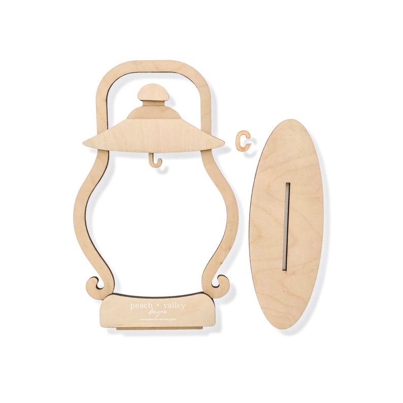 May include: Wooden cutout of a lantern with a hook inside and a base that says "peach + valley designs". The lantern is next to a wooden cutout of a surfboard.