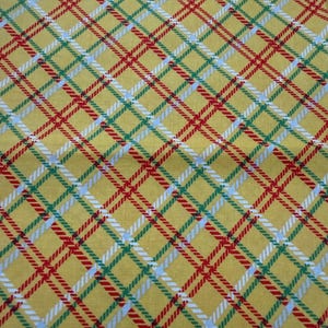May include: Yellow fabric with a plaid pattern. The plaid design features intersecting lines in red, green, white, and light blue, creating a grid-like pattern. The fabric has a slightly textured appearance.