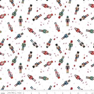 May include: White fabric with a repeating pattern of colorful toy nutcrackers in various poses. The nutcrackers are dressed in red, green, blue, and black uniforms. Small red Christmas trees are scattered throughout the design.