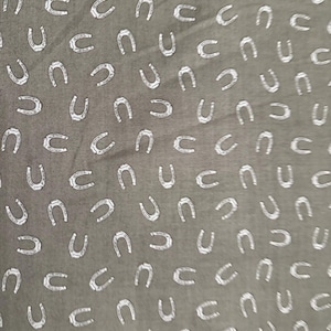 May include: A brown fabric with a white horseshoe pattern.