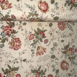 May include: A cream-colored fabric featuring a repeating floral pattern with blooming flowers in shades of red, pink, and yellow, accented by sage green leaves and small blue blossoms on thin, winding brown stems across the entire surface.