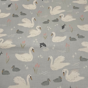 May include: A light blue fabric with a white swan and duck pattern. The swans are swimming in a pond with fish and lily pads. The ducks are swimming in the pond with lily pads.