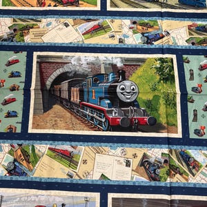 Puede incluir: Panel de tela con imágenes de trenes de dibujos animados, incluido Thomas el Tren. El panel tiene un borde azul oscuro con diseños de postales y mapas. Los trenes son de varios colores, incluyendo azul, verde y rojo.