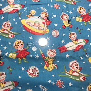 Puede incluir: Tela azul con un diseño retro de temática espacial. El diseño incluye astronautas de dibujos animados, cohetes, platillos volantes, planetas y estrellas. Los astronautas llevan cascos y trajes espaciales rojos, amarillos y verdes. Los cohetes y platillos son rojos, blancos y amarillos.