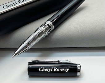 Puede incluir: Bolígrafo negro con detalles plateados y una funda negra. El bolígrafo y la funda están grabados con el nombre "Cheryl Rowsey".