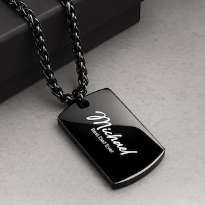 May include: A black dog tag pendant necklace with a matching chain. The tag is rectangular with rounded corners and features the name "Michael" in cursive and the text "Best Dad Ever" in white.