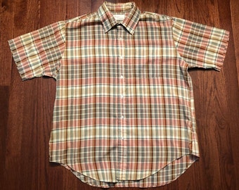 May include: A short-sleeved plaid button-down shirt in a light brown, pink, and white color scheme.