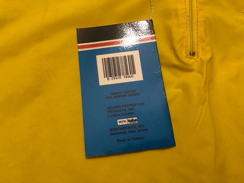 May include: A blue and white tag with a barcode and text that reads "Quality Crafted Foul Weather Apparel Nelson Recreation Products, Inc. Lenexa, Kansas Weather-Rite, Inc. Secaucus, New Jersey Made in Taiwan"