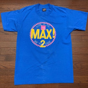 May include: A blue t-shirt with a yellow and pink graphic that says "Live it to the Max! Be the 2 One".