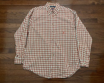 May include: A long-sleeved button-down shirt with a red and white plaid pattern. The shirt has a small embroidered logo on the left chest.