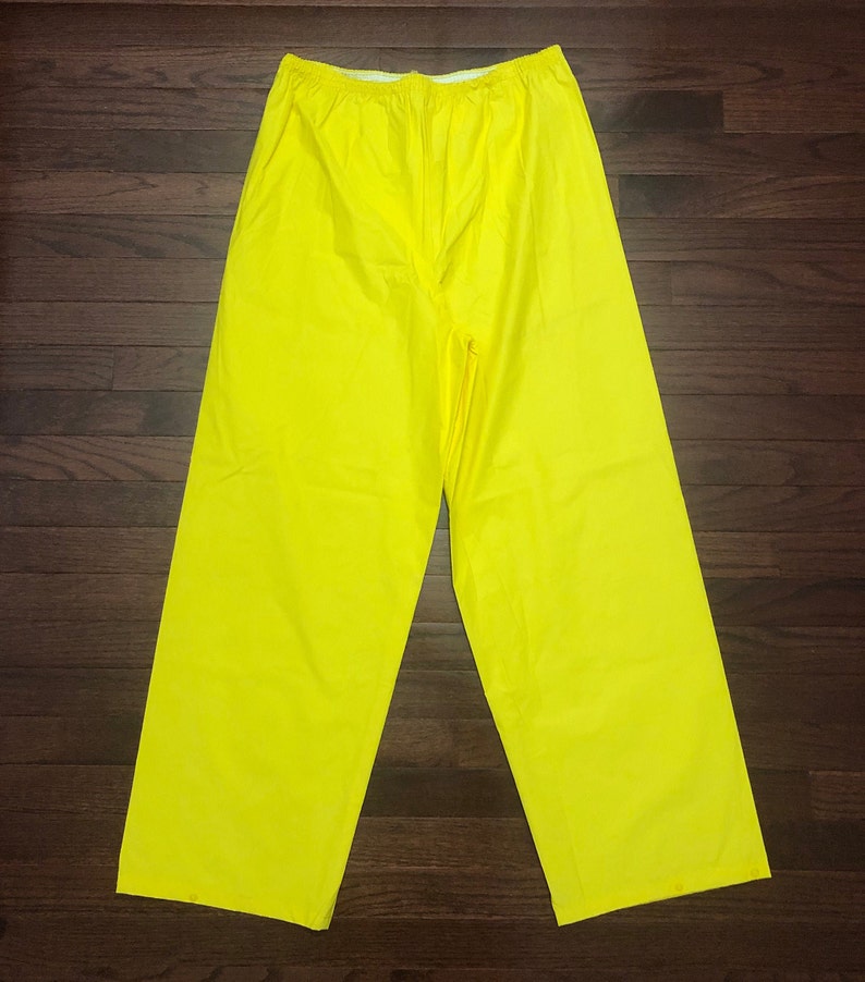May include: A pair of bright yellow waterproof pants. The pants have an elastic waistband and are made of a smooth, shiny material.
