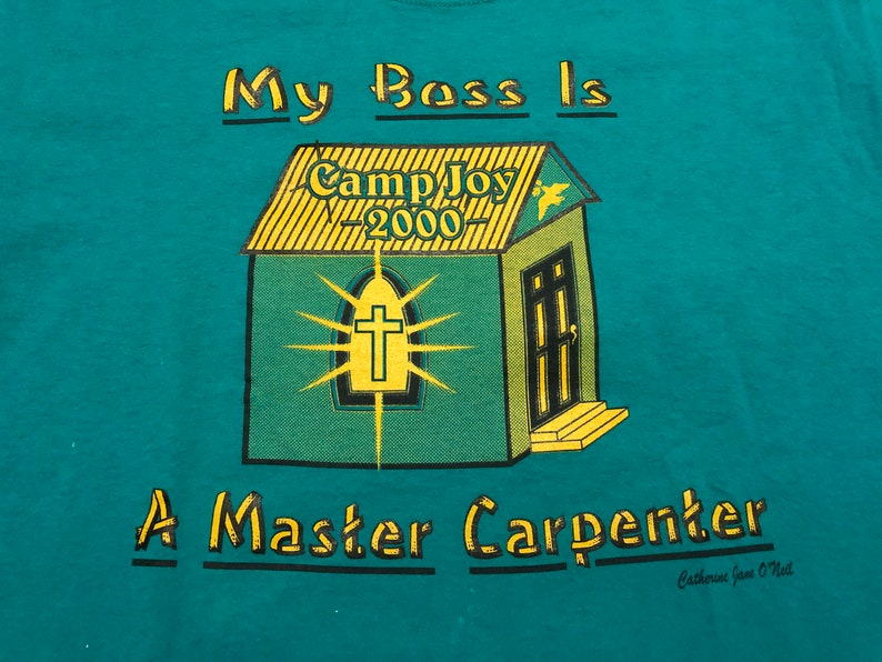 May include: Teal blue t-shirt with a yellow and green illustration of a church with the text "Camp Joy - 2000" on the roof. The text "My Boss Is A Master Carpenter" is printed below the illustration. The text "Catherine Jane O'Neil" is printed in smaller font below the main text.