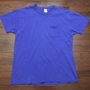 May include: A solid purple t-shirt with a single pocket on the left side.