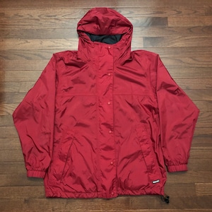 May include: Red hooded jacket with a zipper and snap closure. The jacket has a drawstring hood and two pockets. The brand name "REI" is visible on the bottom right side of the jacket.