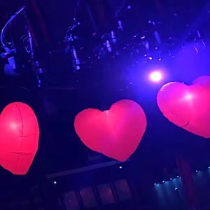 Bright LED inflatable love hearts lighting up an outdoor wedding venue.