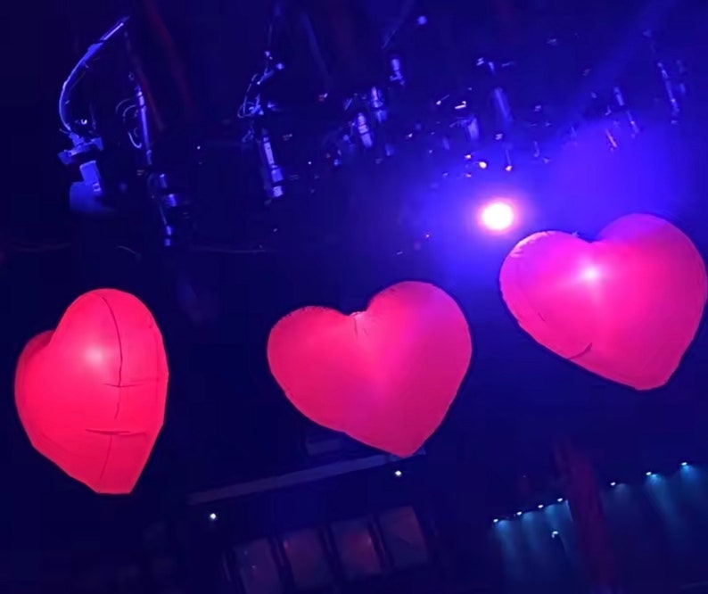 Bright LED inflatable love hearts lighting up an outdoor wedding venue.