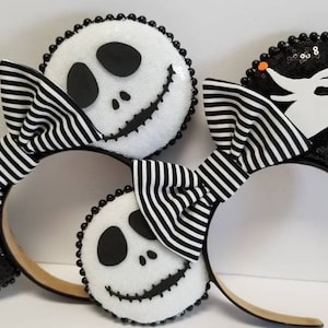 May include: Black and white striped bow headband with two black and white ears. One ear features a white Jack Skellington face on a black background. The other ear features a white Zero silhouette on a black background.