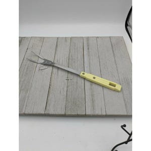 Peut inclure: Une fourchette à griller en acier inoxydable avec un manche jaune et trois dents.