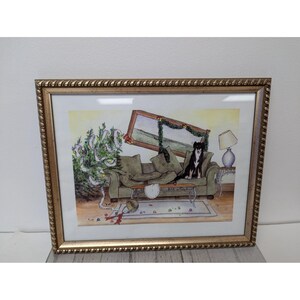 May include: A framed watercolour painting shows a living room in disarray. A dog sits on a green sofa, surrounded by a fallen Christmas tree and scattered decorations. The painting is in a gold-coloured frame.