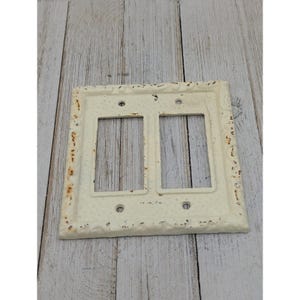 May include: White cast iron double light switch cover with an ornate design.