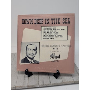May include: Vintage vinyl record album cover titled "Down Deep in the Sea" featuring gospel favorites. The cover is a light pink with the album title in bold, dark text. A black and white photo of Harry Hadley Schyde is on the cover.