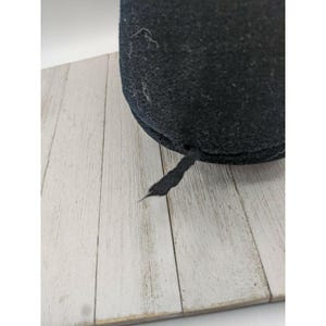 May include: Black felt hat with a black ribbon tied at the back.