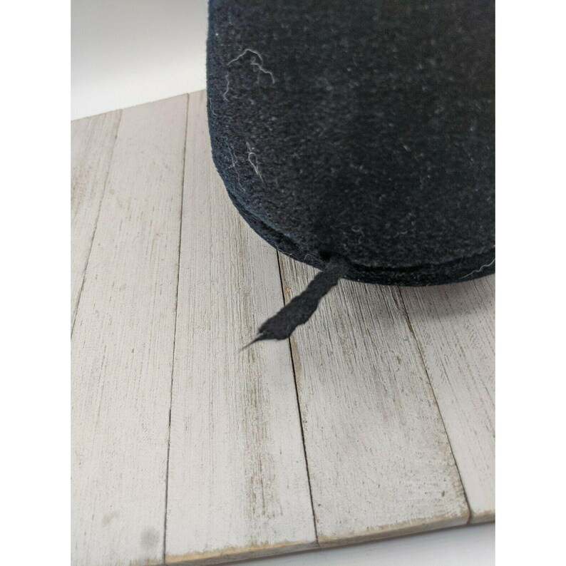 May include: Black felt hat with a black ribbon tied at the back.
