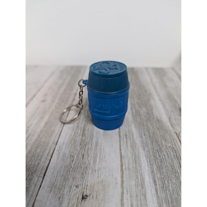 May include: Blue plastic barrel keychain with a metal ring. The barrel has a raised design of a barrel with the words "Old Smugglers" on it.