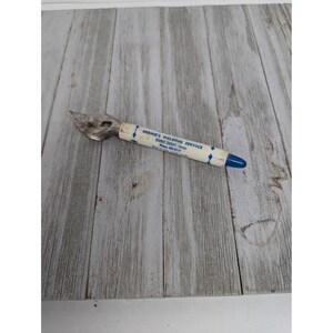 May include: A vintage bottle opener with a metal blade and a white handle. The handle has blue diamond shapes and text that reads "BERNIE'S WELDING SERVICE". The end of the handle is blue.