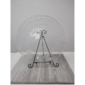 May include: A clear glass serving platter with a raised design of a turkey. The platter is on a black metal stand.