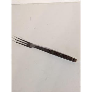 Op de afbeelding: Een metalen vork met drie tanden en een houten handvat. Het handvat is donkerbruin en heeft drie klinknagels. De vork is ontworpen voor het serveren van voedsel.
