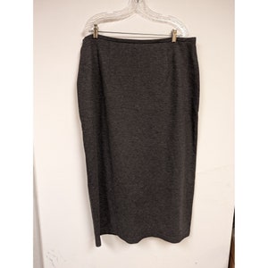 May include: A long, dark gray skirt with a straight silhouette. The skirt is made of a soft, stretchy fabric and has a simple, classic design.