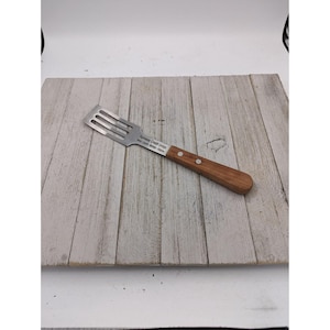 May include: A stainless steel spatula with a wooden handle. The spatula has three slots and the text "Formway Credit Union" is printed on the metal. The handle is a light brown color and is attached to the metal with two rivets.