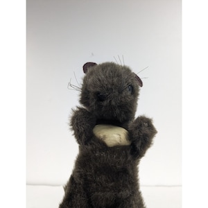 May include: A brown plush toy resembling a small animal, possibly a beaver or a squirrel, holding a light brown, round object in its paws.