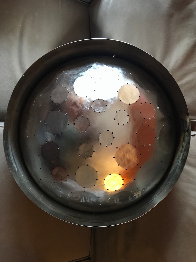 May include: A silver colander with a round, bowl-shaped design and a large number of small holes. The colander is made of metal and has a shiny, reflective surface.