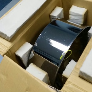May include: A silver metal drum is packaged in a brown cardboard box with white foam padding. The drum is shiny and reflective.