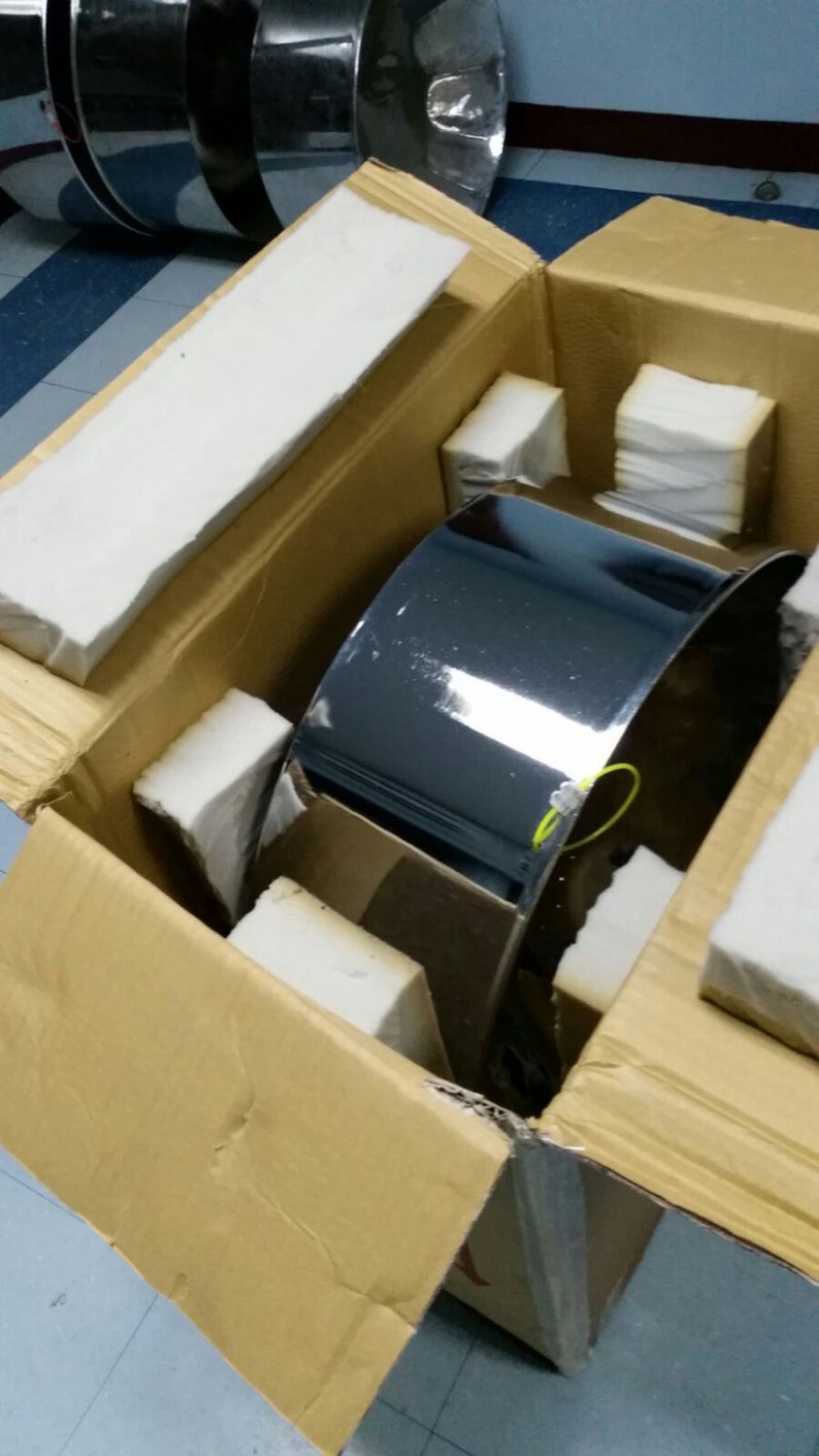May include: A silver metal drum is packaged in a brown cardboard box with white foam padding. The drum is shiny and reflective.
