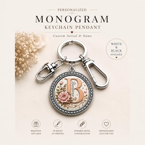 May include: A silver-toned circular keychain pendant featuring a large rose-gold letter B with the name Barbara printed vertically. The design includes a pink floral motif, small stars, and a decorative border. It has a metal ring and two lobster clasps.