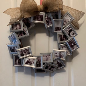 May include: A wreath made of small silver picture frames, each holding a black and white photo. The wreath is decorated with a large burlap bow.