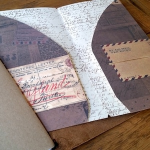 Puede incluir: Un diario de cuero marrón con estética vintage. La cubierta presenta una solapa con un bolsillo y un inserto de papel decorativo con el texto "Registered Letter" y "By Air Mail Par Avion".