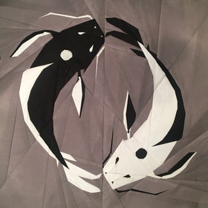 May include: A black and white origami fish design on a gray background. The fish are facing each other and appear to be swimming in opposite directions.