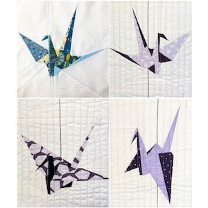 May include: Four white fabric squares with a colorful origami crane on each. The cranes are made of different patterned fabrics in shades of blue, purple, and black.