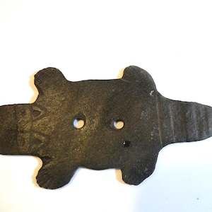 May include: A dark brown, turtle-shaped button with two holes. The button has a textured surface and a slightly irregular shape, suggesting it may be handmade. The button is likely for clothing or craft projects.