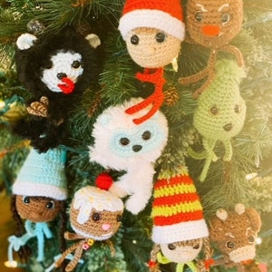 以下が含まれることがあります： クリスマスツリーに飾られた、かぎ針編みで作ったオーナメントの集まり。オーナメントには、ジンジャーブレッドマン、雪だるま、トナカイ、ノーム、白黒の生き物が含まれています。