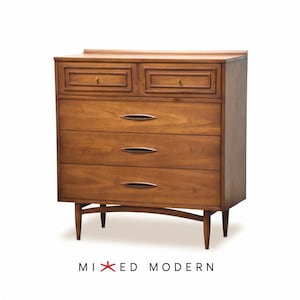 May include: A brown wooden dresser featuring two small top drawers with rectangular molding and three larger lower drawers with elongated, dark, almond-shaped pulls. The piece stands on four tapered legs with a curved support rail. Text reads MIXED MODERN.