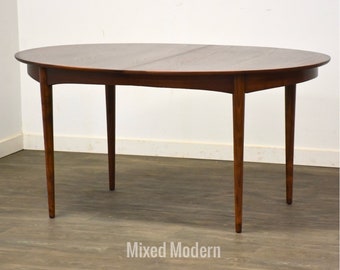 May include: A mid-century modern oval dining table with a rich brown finish. The table features a smooth tabletop and four slender, tapered legs. The table is approximately 60 inches long and 40 inches wide.