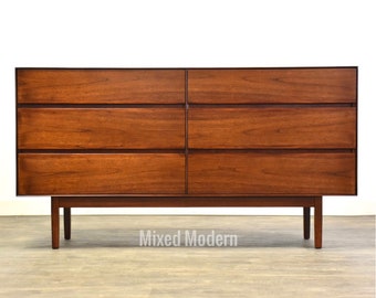 May include: A six-drawer dresser made of dark wood with a simple design. The dresser has a rectangular shape and sits on four legs.