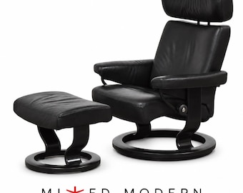 May include: A black leather recliner chair with a matching ottoman, both featuring curved dark wood circular bases. The chair has a high backrest with an integrated headrest and padded armrests. The text MIXED MODERN is printed below.