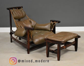 May include: A mid-century modern lounge chair and ottoman set. The chair features a dark wood frame, olive green leather cushions, and a woven back. The matching ottoman has a similar design. The set is a stylish addition to any living space.